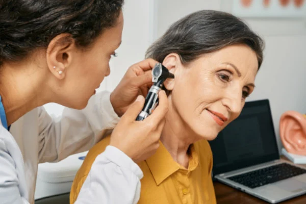 A woman receives a hearing examination with an otoscope